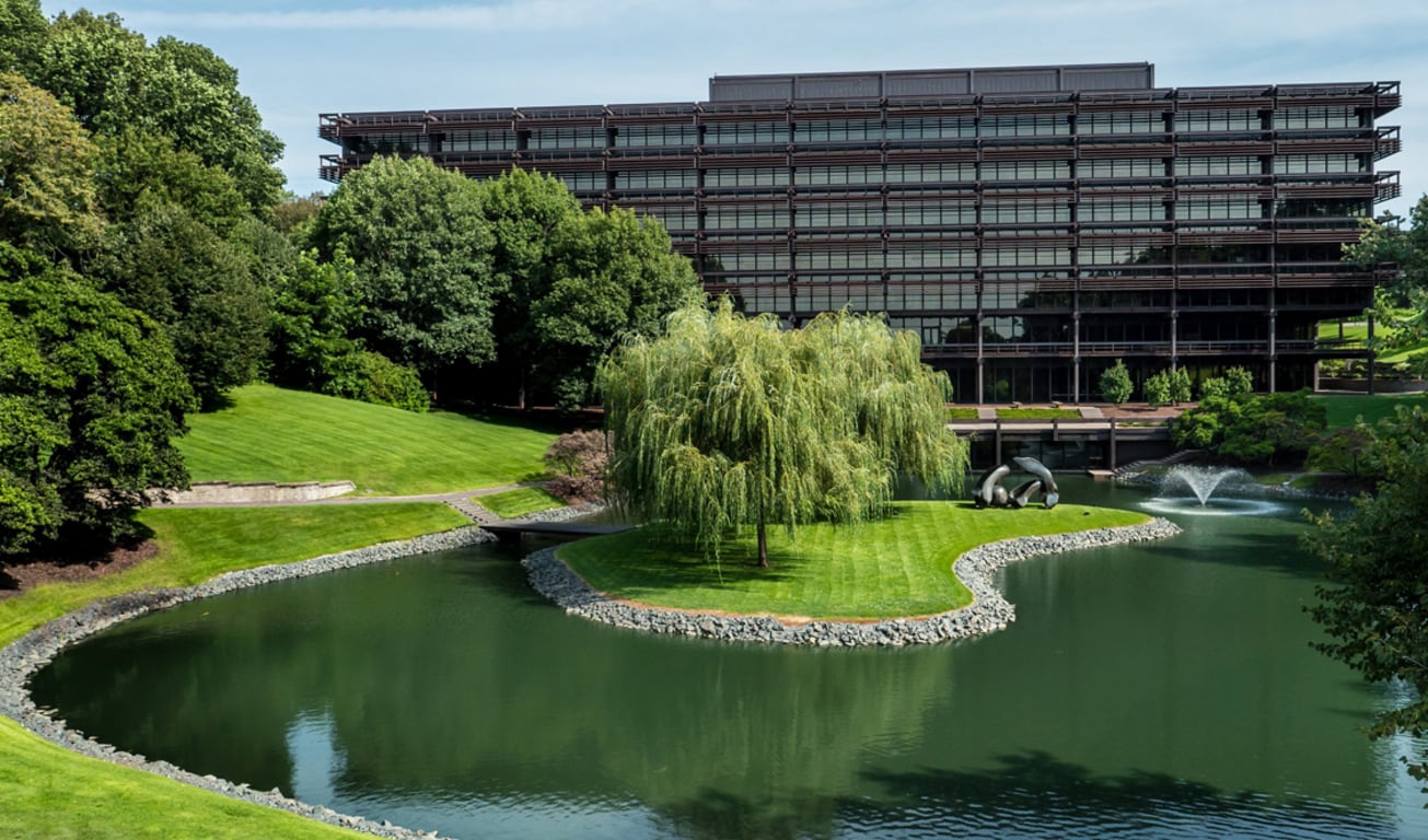 Vue aérienne de la partie avant du siège social John Deere avec l'étang et les arbres en avant-plan