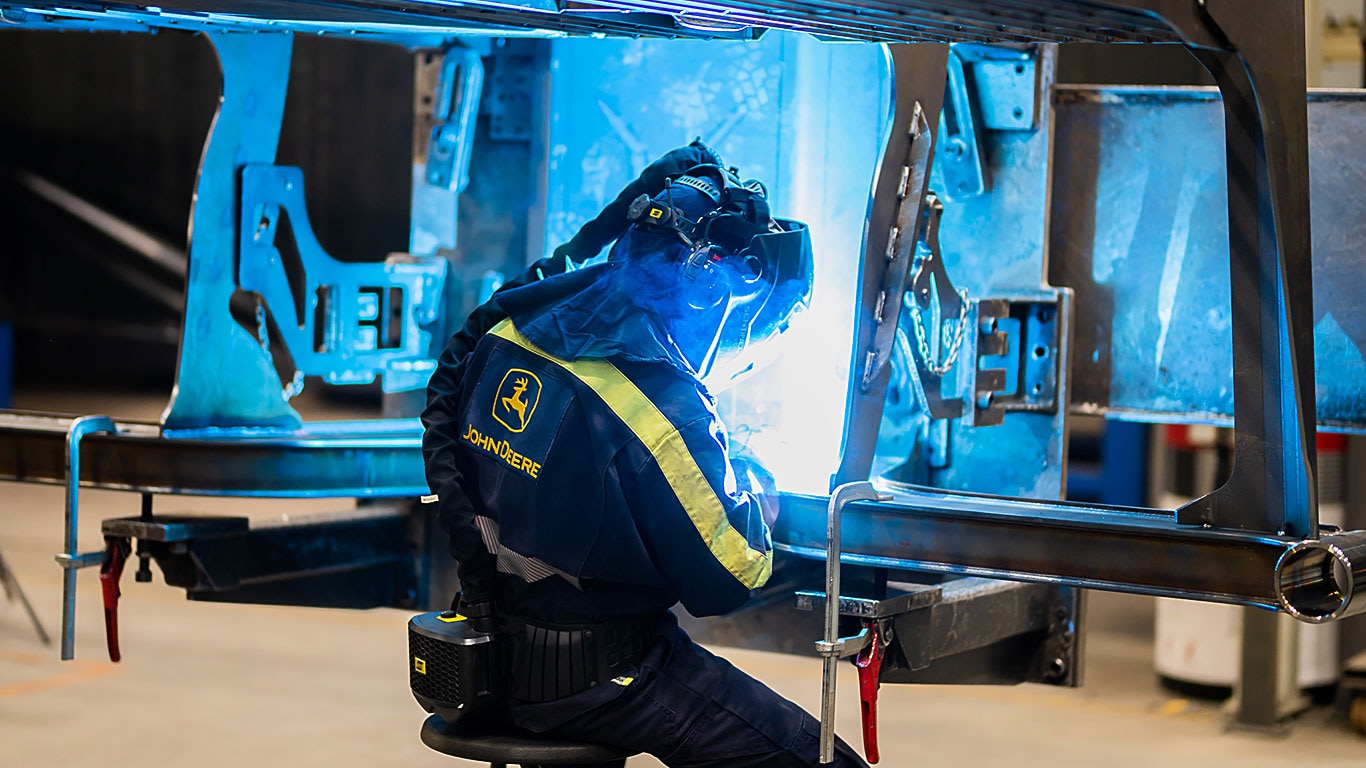 Une personne soude une grille avant d’une machine forestière