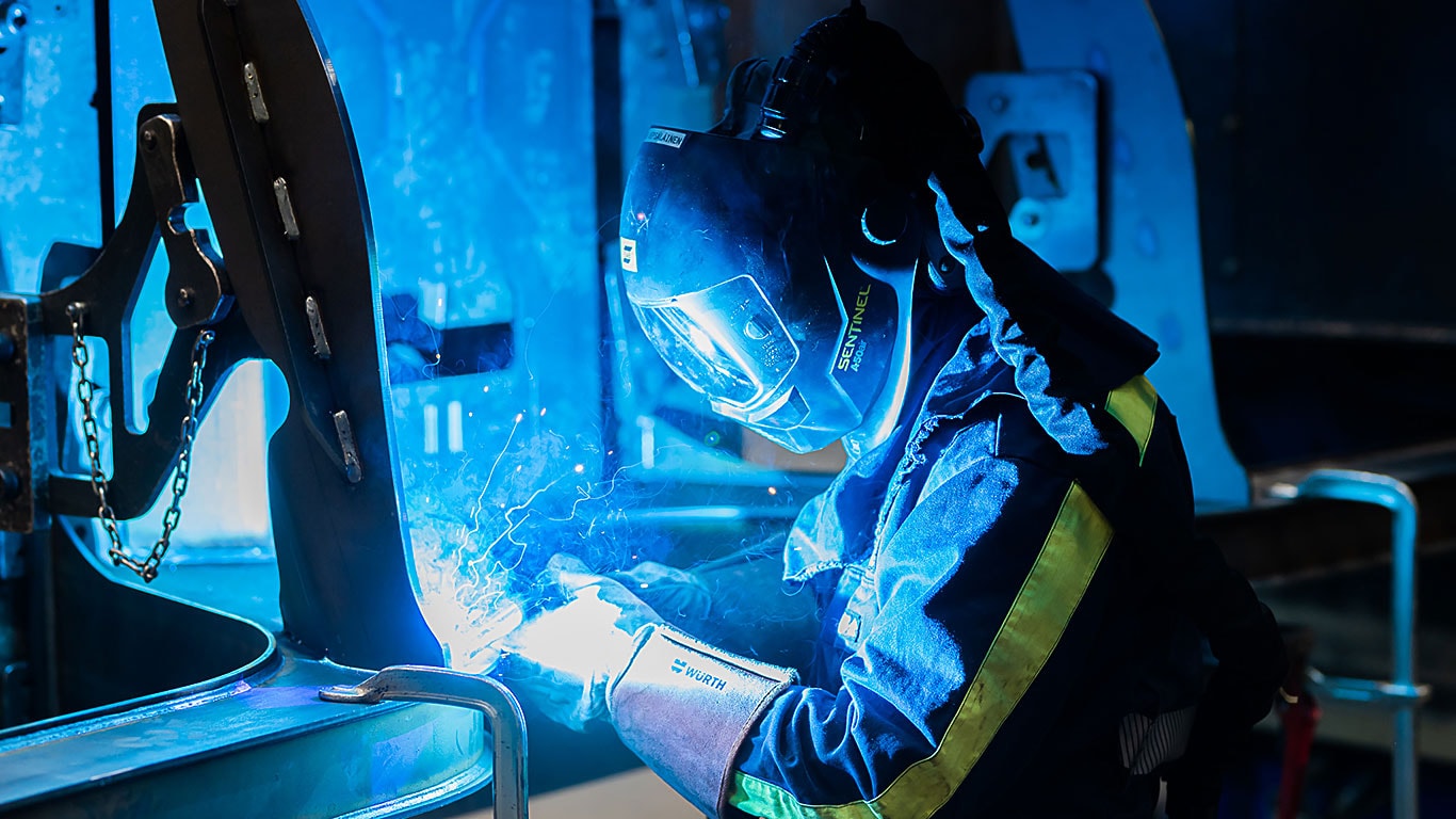 Une personne soude un espace de chargement d’une machine forestière