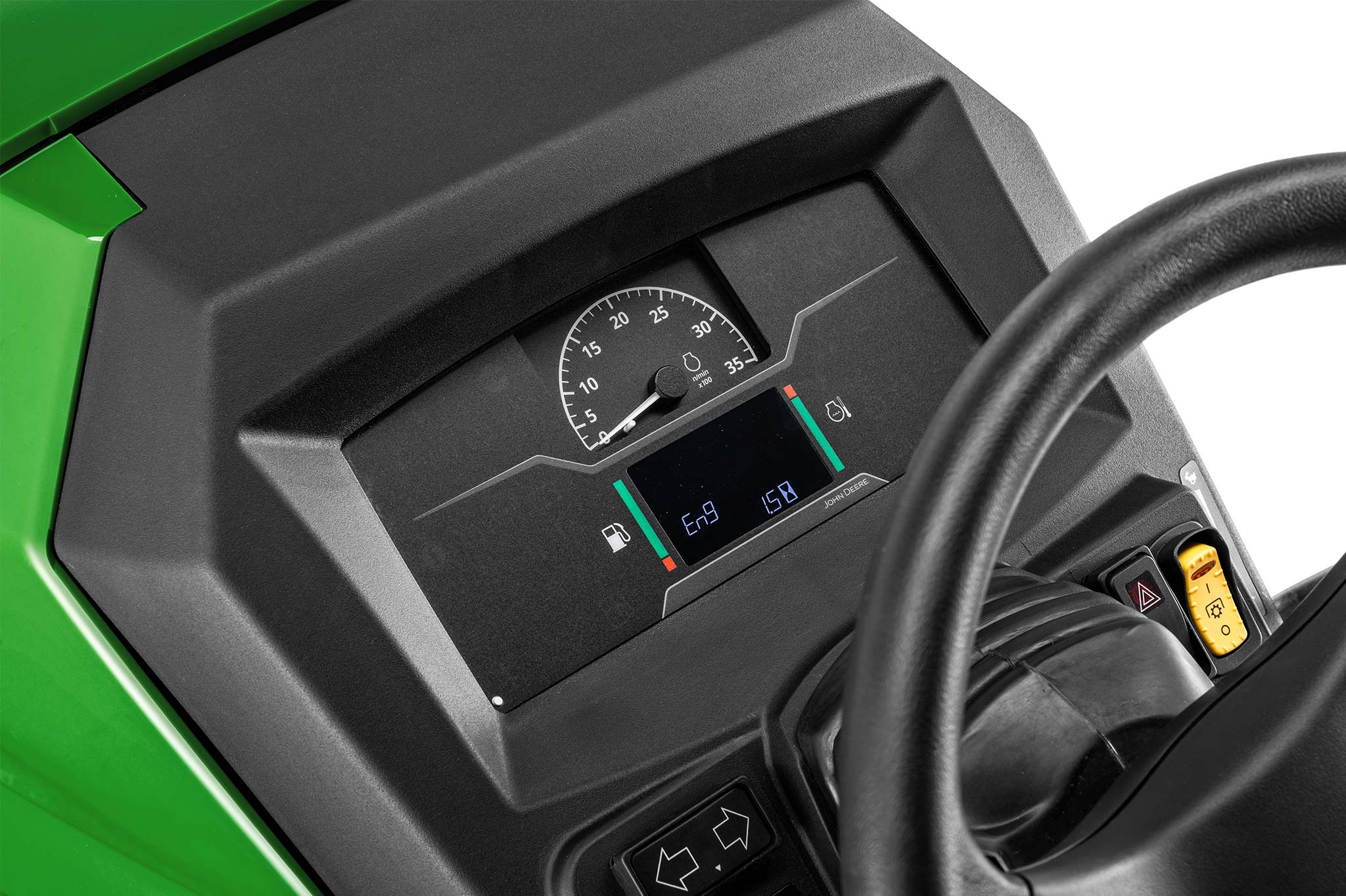 Gros plan sur le tableau de bord d’un tracteur compact John Deere, avec console numérique, jauges et volant