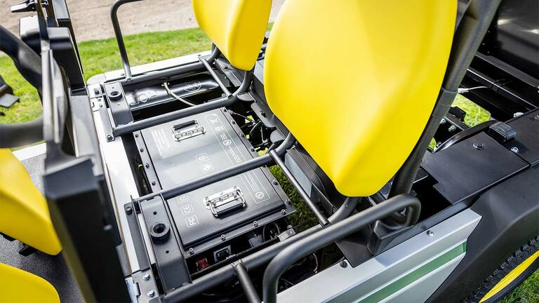 Gros plan sur deux batteries au lithium installées sous les sièges jaune vif d’un véhicule utilitaire électrique Gator&nbsp;GS John&nbsp;Deere.