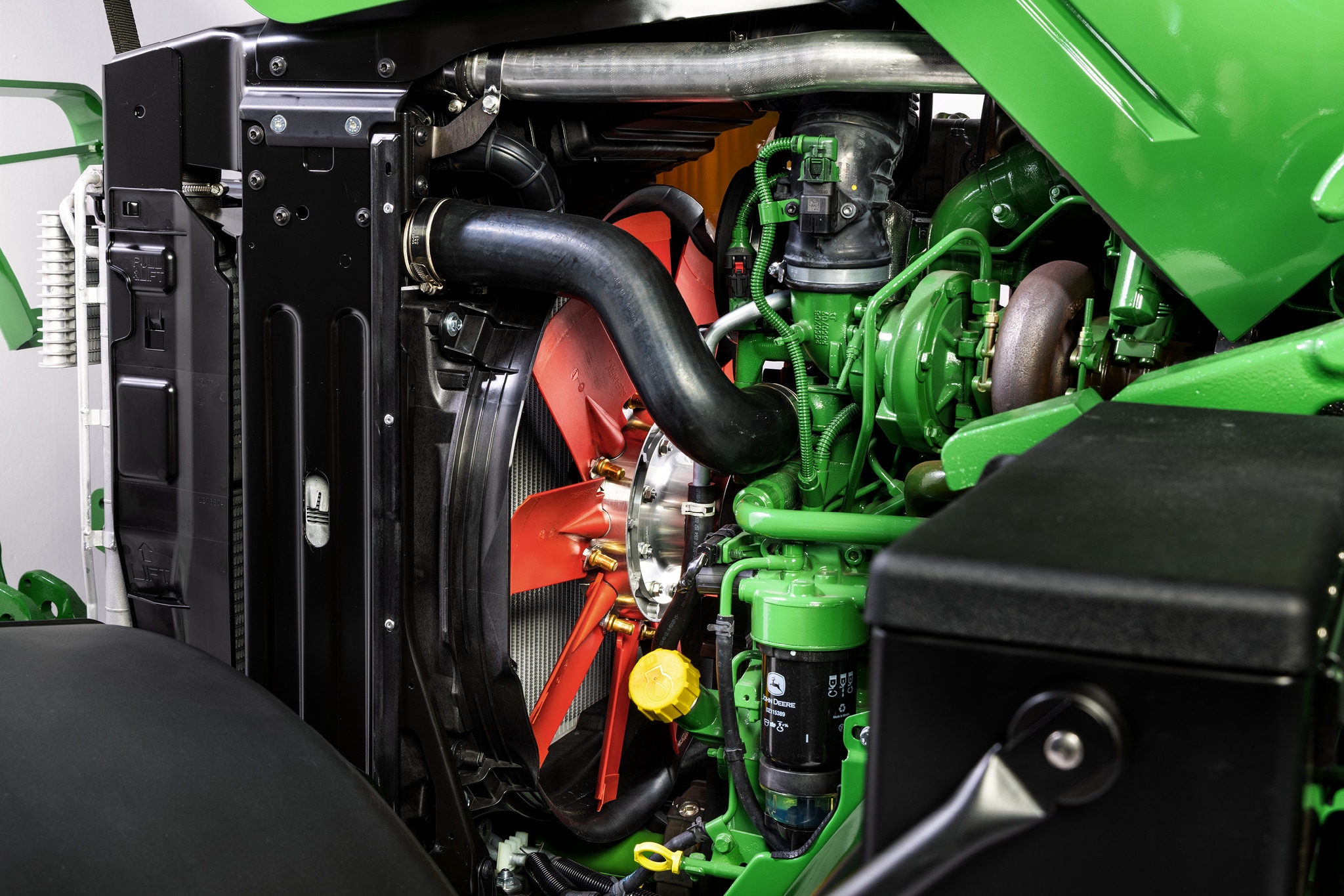 Close-up van het motorcompartiment van de John Deere 6M Series met focus op het koelsysteem en de motorcomponenten.