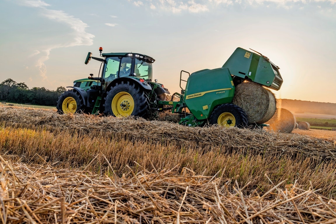 Presse à balles John Deere F442M tirée par un tracteur John Deere 6M éjectant une balle de paille