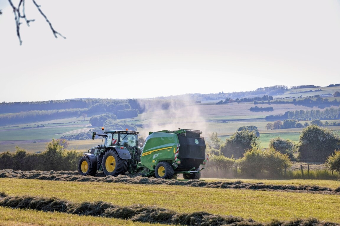 John Deere V462R tirée par un tracteur John Deere 6R 185 pressant du foin