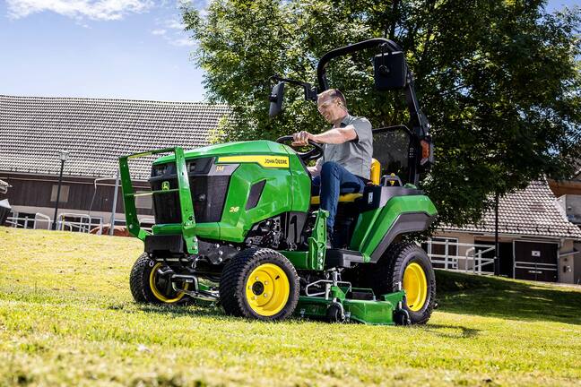 Un utilisateur tondant une pente herbeuse à l’aide d’un tracteur compact John Deere équipé d’une unité de coupe ventrale